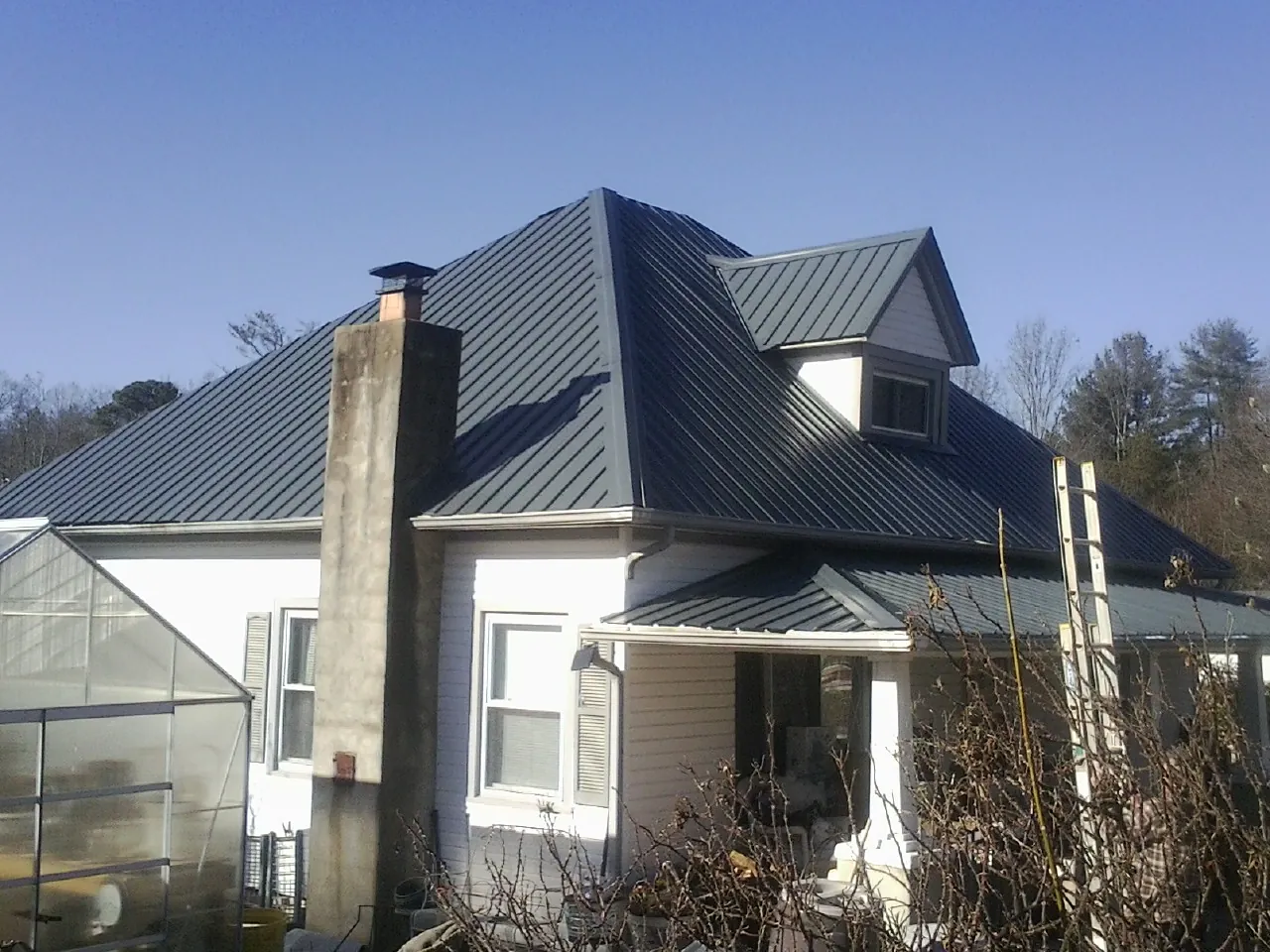 Dark blue standing seam metal roof on a white farmhouse with dormer — Slate & Tile Roof Repair by Roofing Brothers in Stilwell