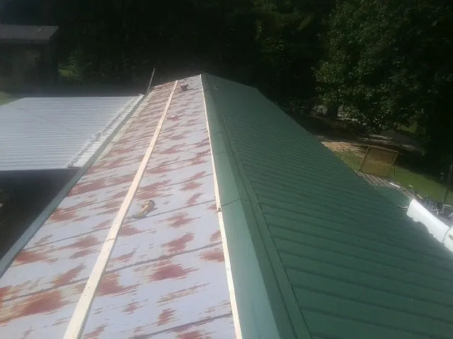 Old rusted panels beside newly installed green metal roofing — Wind Damage Roof Repair by Roofing Brothers in Stilwell
