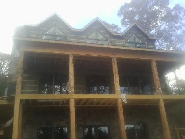 Dormers and porch framing on a large log home under construction — Roof Coating work by our crew in Stilwell