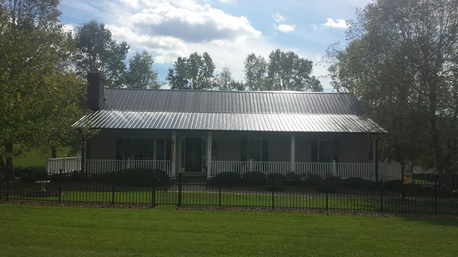 Gray metal roof on a brick ranch with a full width front porch — Gutter Guard Installation work by our crew in Stilwell