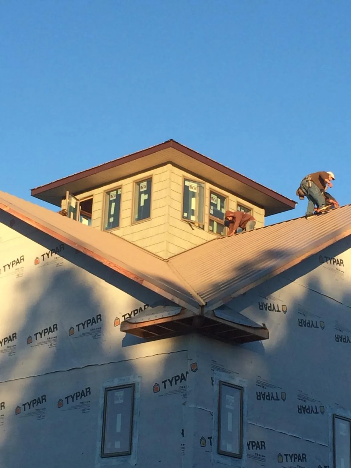 Roofers working around a rooftop cupola on a new metal roof at sunset — Roof Waterproofing in Stilwell by Roofing Brothers